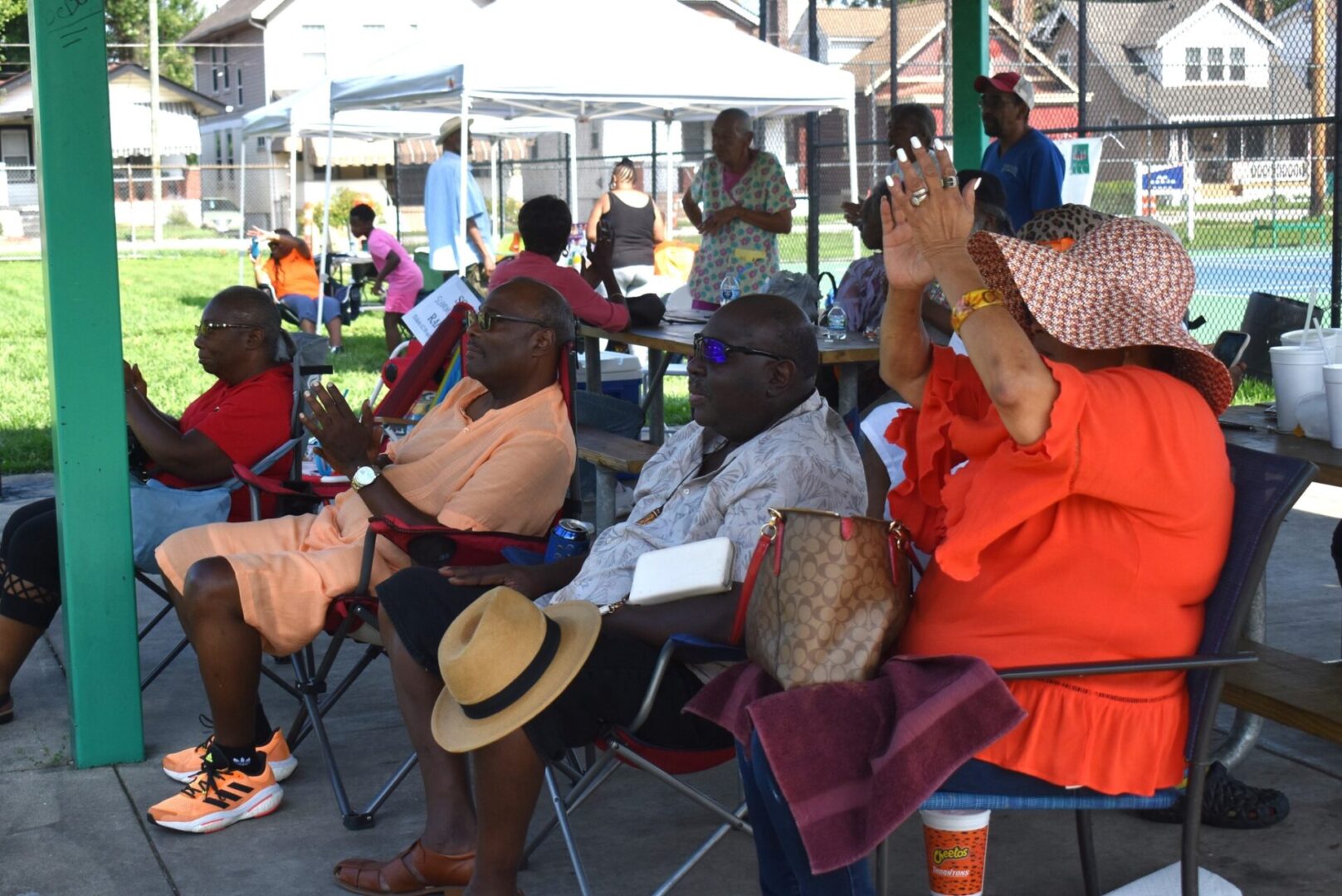 People seated outdoors, some raising their hands, engaged in an event.
