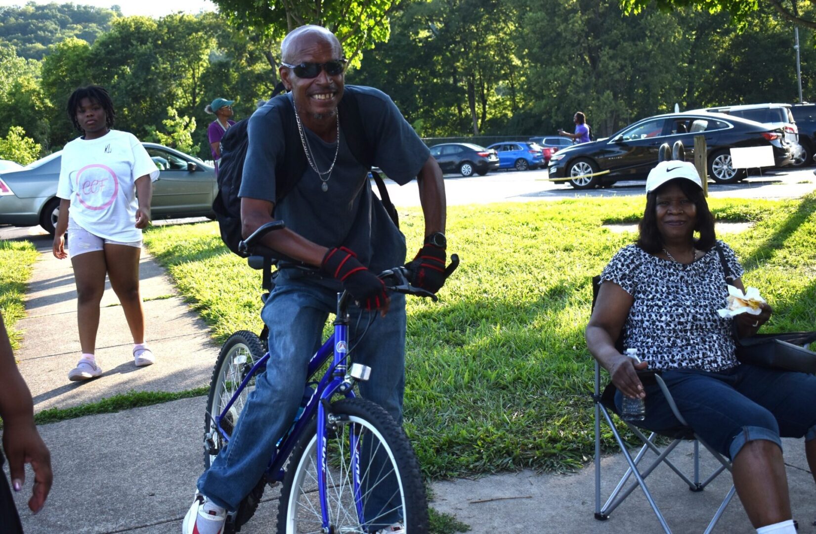 Man in sunglasses riding a bicycle on a sunny day.