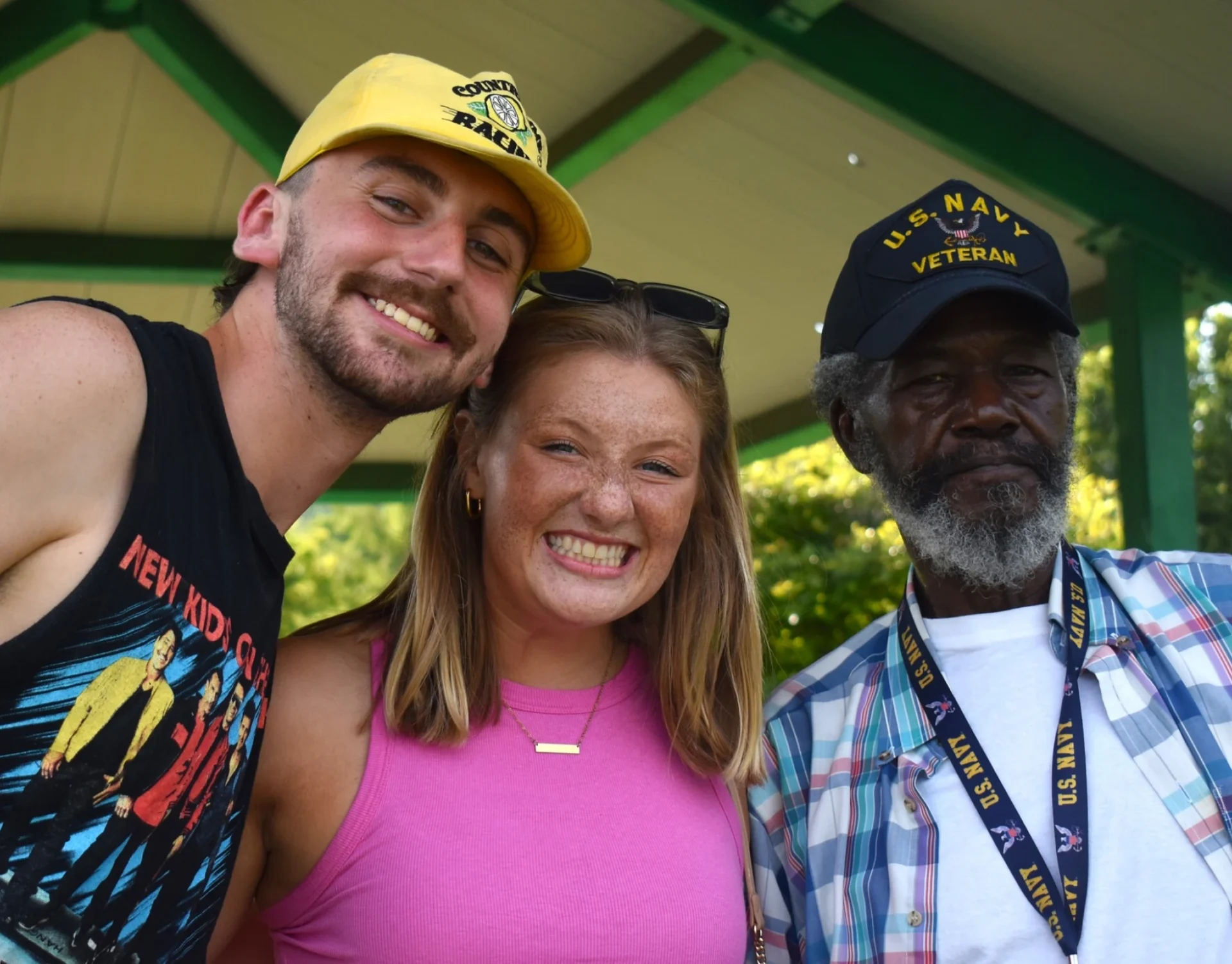 Three people smiling under a pavilion